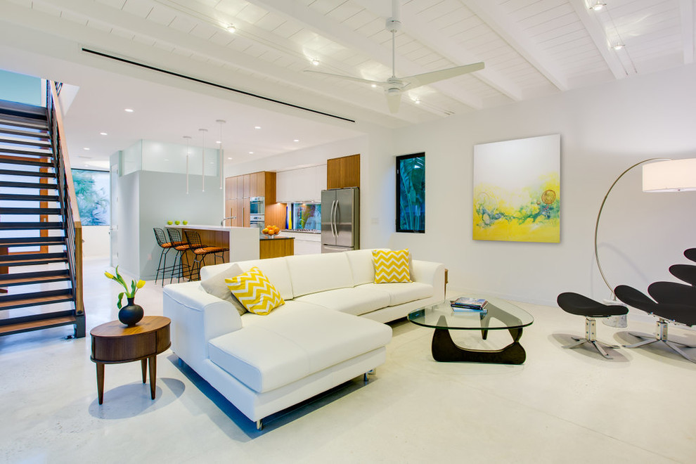 Modelo de salón abierto minimalista de tamaño medio con paredes blancas, suelo de cemento y televisor colgado en la pared