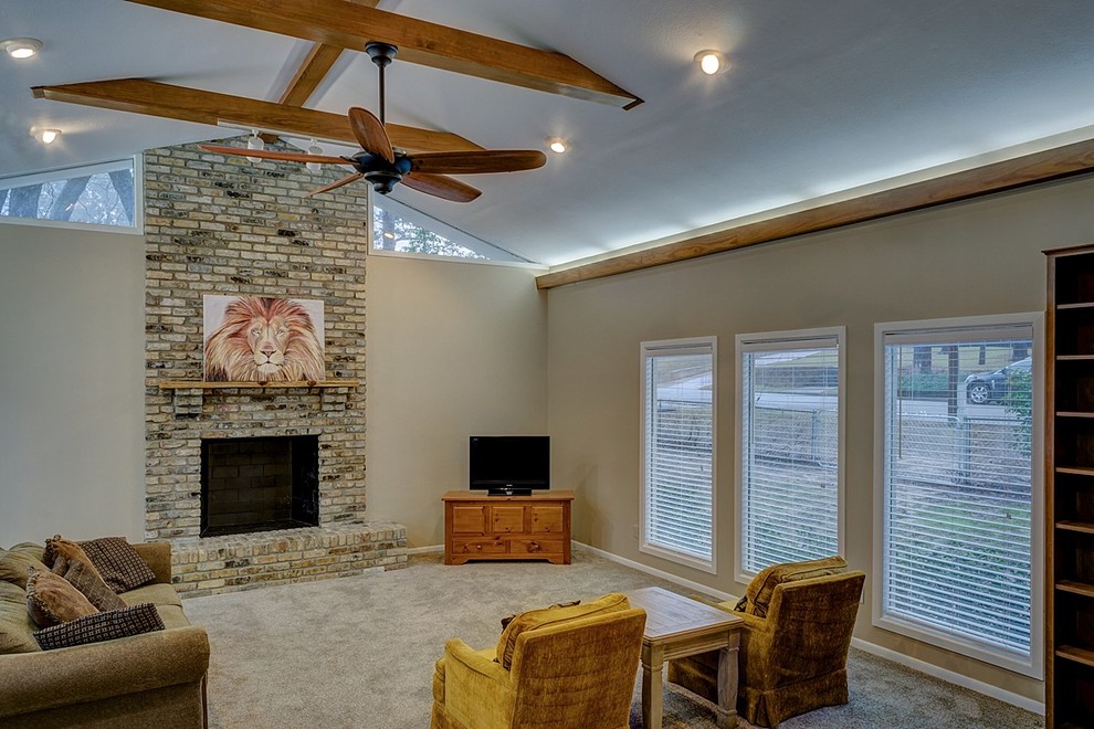 This is an example of a large retro enclosed living room in Austin with beige walls, carpet, a standard fireplace, a brick fireplace surround and a freestanding tv.