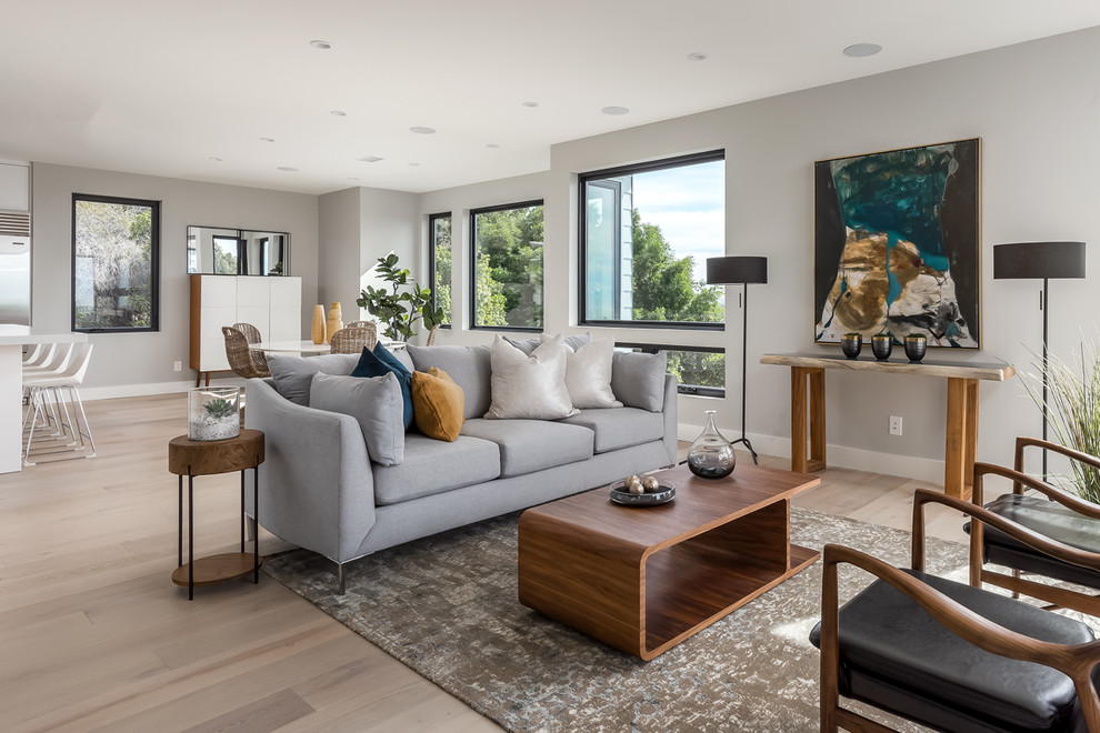 Example of a large trendy open concept light wood floor and beige floor living room design in San Diego with no tv, white walls and no fireplace