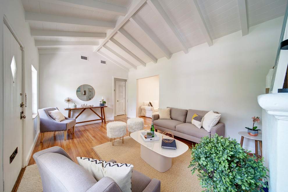 На фото: гостиная комната среднего размера в современном стиле с белыми стенами, стандартным камином и коричневым полом с
