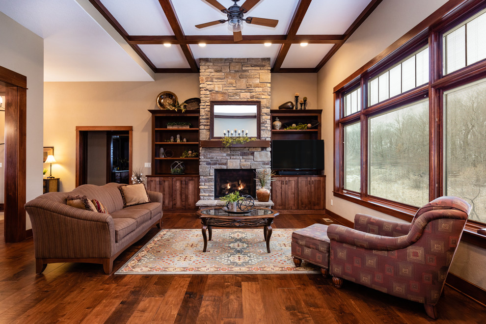 This is an example of a large traditional open plan living room in Other with beige walls, medium hardwood flooring, a standard fireplace, a stone fireplace surround, a built-in media unit and brown floors.