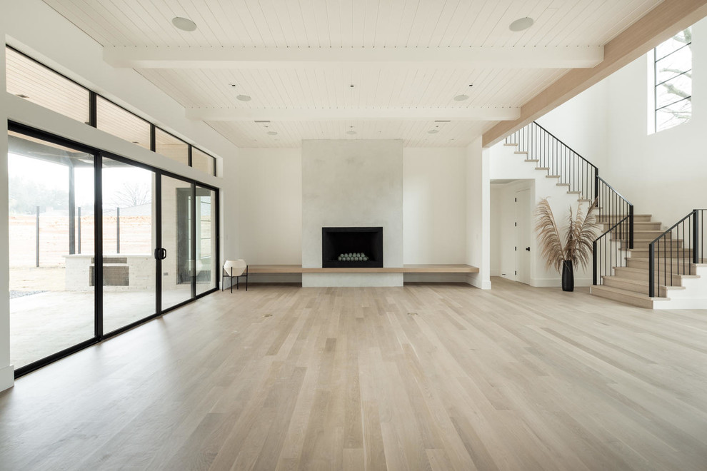 Large minimalist formal and open concept light wood floor and brown floor living room photo in Dallas with white walls, a standard fireplace, a concrete fireplace and a wall-mounted tv