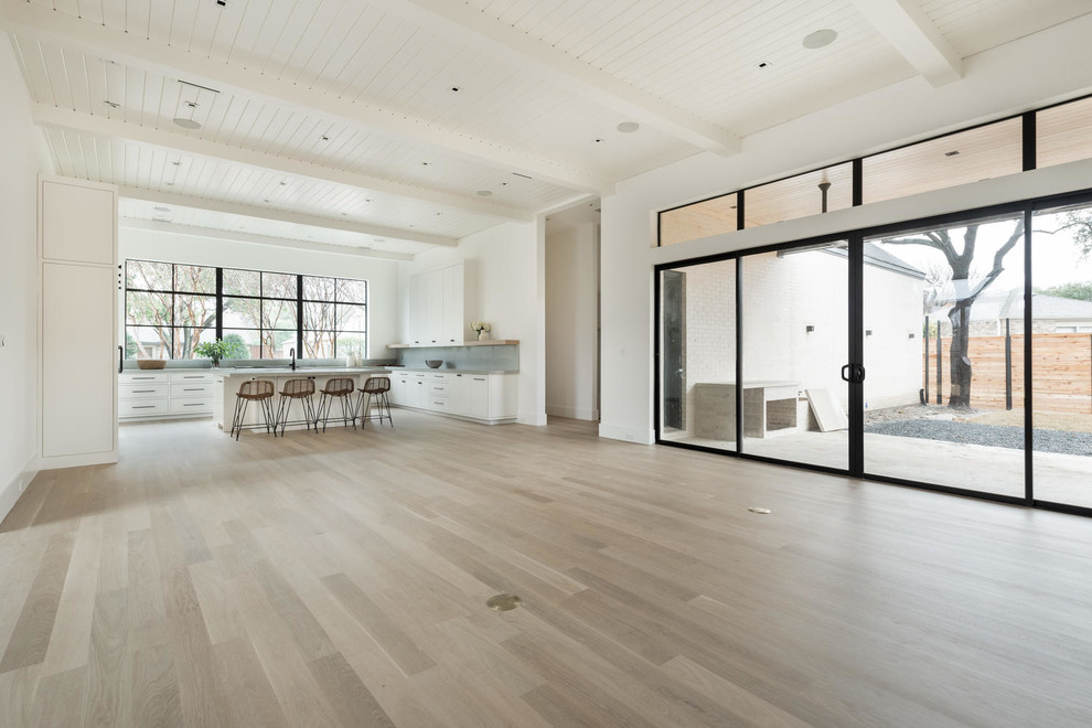Example of a large minimalist formal and open concept light wood floor and brown floor living room design in Dallas with white walls, a standard fireplace, a concrete fireplace and a wall-mounted tv
