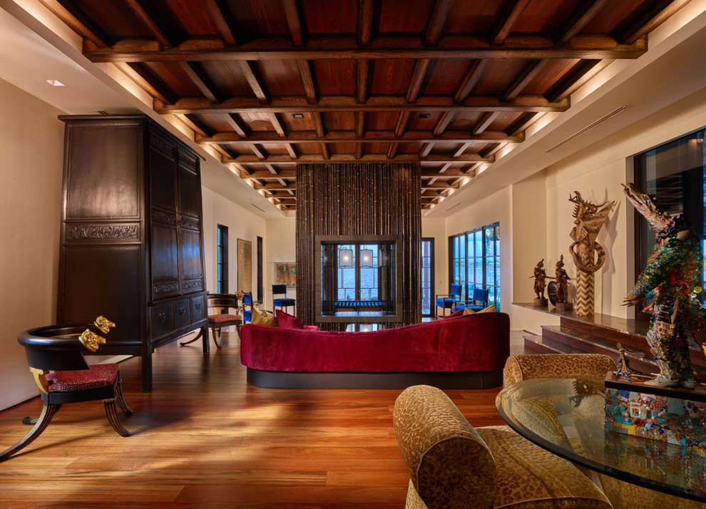 Photo of an expansive world-inspired formal enclosed living room in Other with beige walls, medium hardwood flooring, a two-sided fireplace, a wooden fireplace surround, no tv and brown floors.