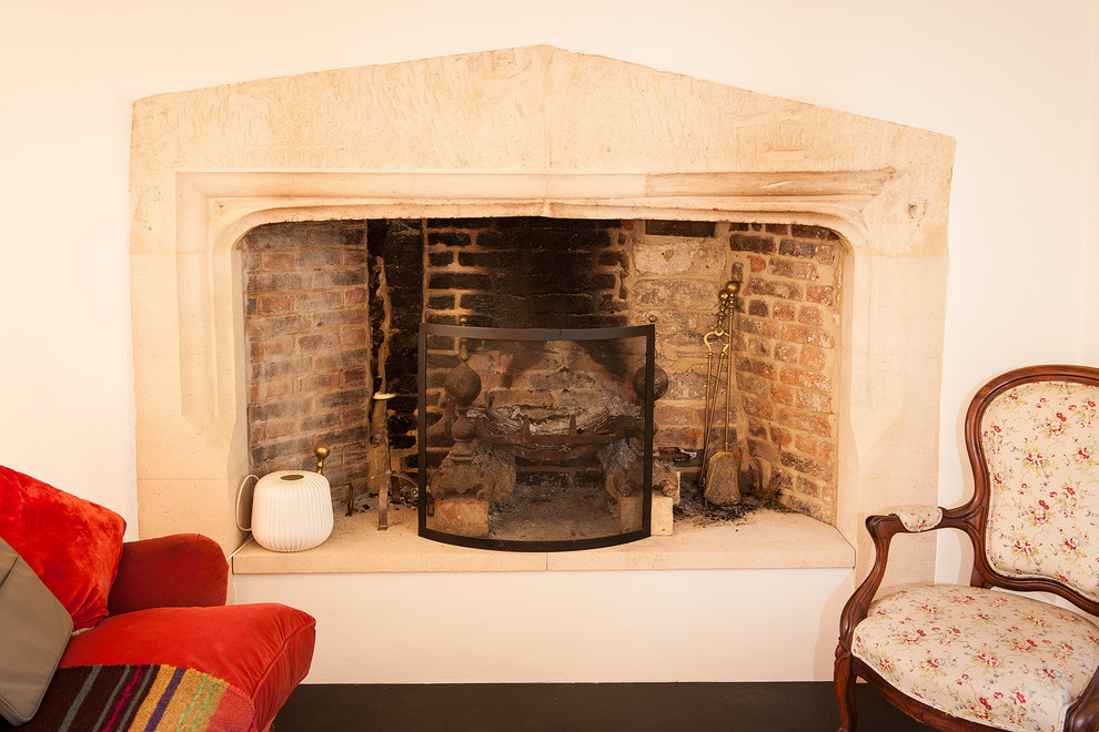 Großes, Repräsentatives, Fernseherloses, Abgetrenntes Country Wohnzimmer mit weißer Wandfarbe, Kamin, Kaminumrandung aus Stein, gebeiztem Holzboden und braunem Boden in Oxfordshire