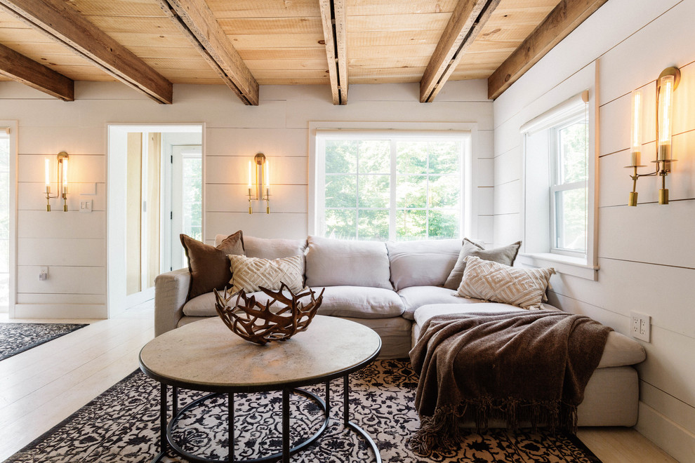 Imagen de salón abierto de estilo de casa de campo de tamaño medio con paredes blancas, suelo de madera clara, estufa de leña, marco de chimenea de hormigón, televisor colgado en la pared y suelo blanco