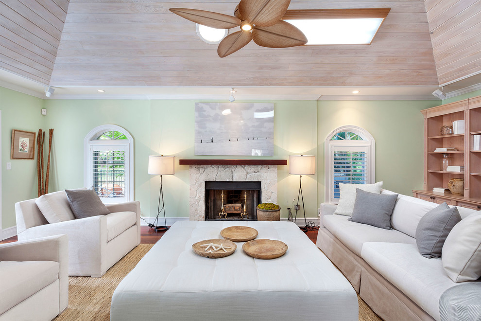 Mid-sized beach style enclosed medium tone wood floor and red floor living room photo in Miami with green walls, a standard fireplace, a stone fireplace and no tv