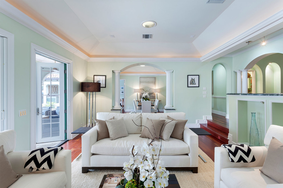 Mittelgroßes, Repräsentatives, Fernseherloses, Offenes Mediterranes Wohnzimmer mit grüner Wandfarbe, braunem Holzboden, rotem Boden, Kamin und verputzter Kaminumrandung in Miami