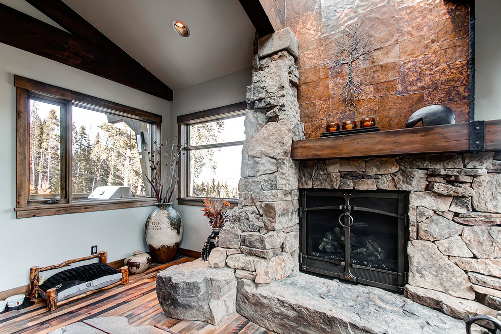 Uriges Wohnzimmer mit grauer Wandfarbe, dunklem Holzboden, Kamin und Kaminumrandung aus Stein in Denver