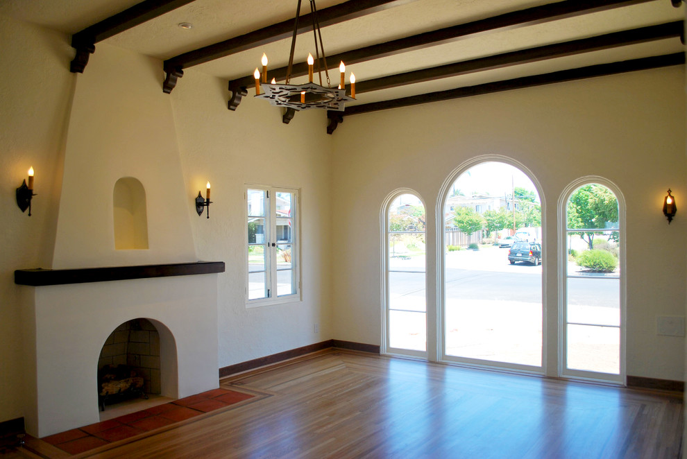 Repräsentatives, Abgetrenntes Mediterranes Wohnzimmer mit weißer Wandfarbe, braunem Holzboden, Kamin und verputzter Kaminumrandung in San Diego