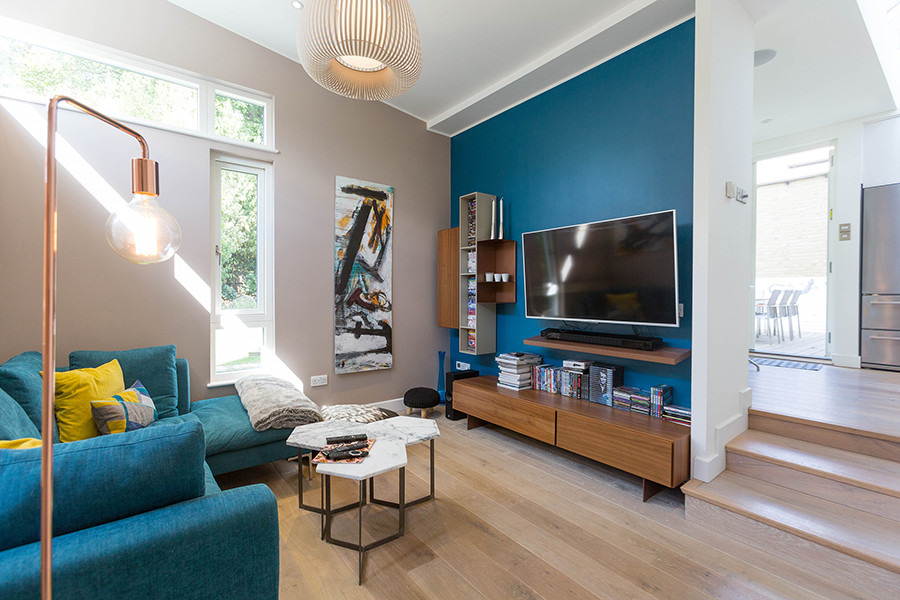 На фото: открытая гостиная комната среднего размера в современном стиле с синими стенами, светлым паркетным полом и телевизором на стене с