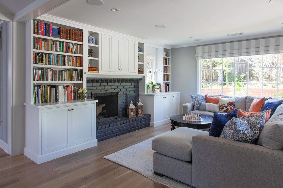 Klassisches Wohnzimmer mit grauer Wandfarbe, braunem Holzboden, Kamin, Kaminumrandung aus Backstein und braunem Boden in San Diego