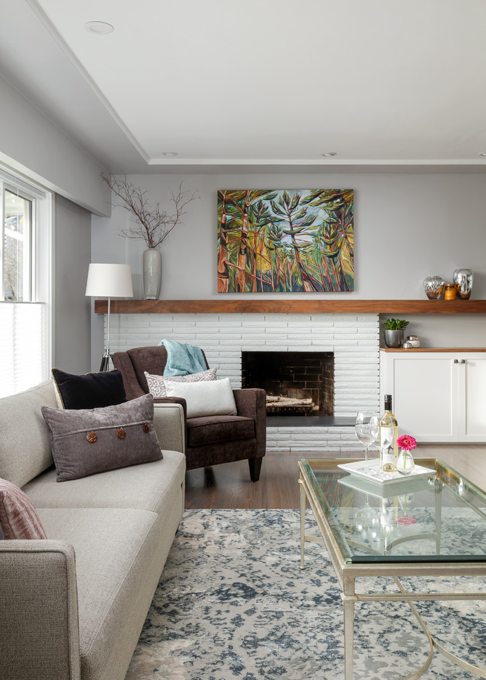 Mittelgroßes, Offenes Modernes Wohnzimmer mit grauer Wandfarbe, hellem Holzboden, Kamin, Kaminumrandung aus Backstein und grauem Boden in Vancouver