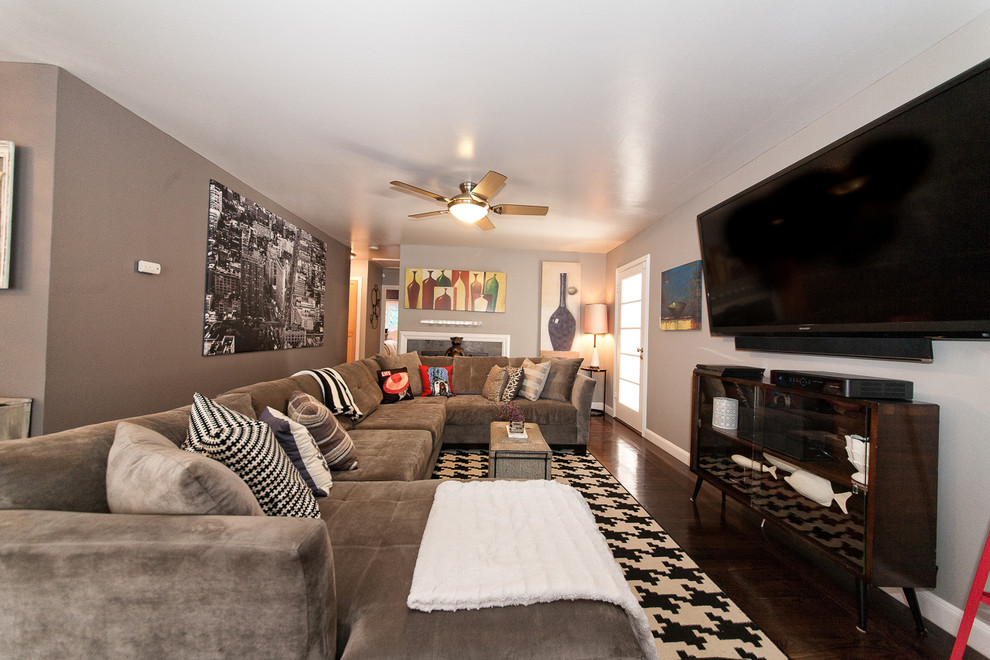 На фото: открытая гостиная комната среднего размера в стиле ретро с серыми стенами, темным паркетным полом, печью-буржуйкой, фасадом камина из камня и телевизором на стене с