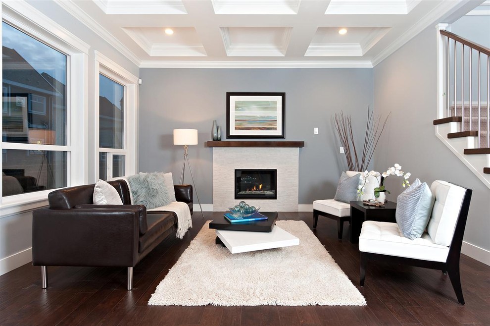 На фото: гостиная комната в современном стиле с серыми стенами, темным паркетным полом и стандартным камином с