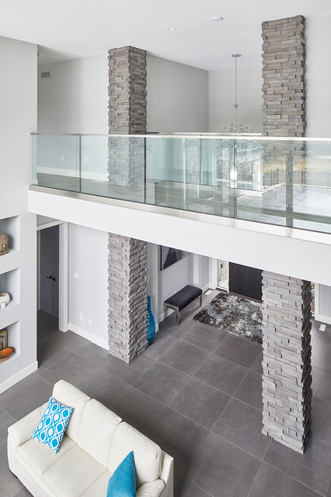 Стильный дизайн: огромная парадная, двухуровневая гостиная комната в стиле модернизм с серыми стенами, полом из сланца, горизонтальным камином, фасадом камина из камня и серым полом без телевизора - последний тренд