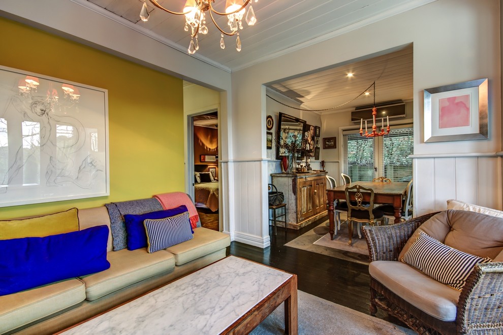 Offenes Stilmix Wohnzimmer mit gelber Wandfarbe und dunklem Holzboden in Melbourne