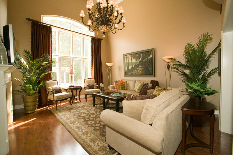 This is an example of a large traditional formal enclosed living room in Dallas with beige walls, dark hardwood flooring, a two-sided fireplace, a wooden fireplace surround, a wall mounted tv and brown floors.