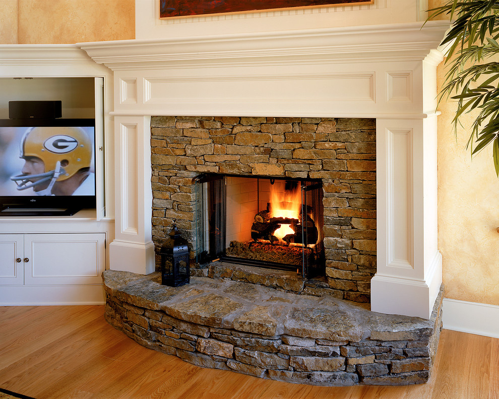 Example of a classic living room design in New York with beige walls, a standard fireplace and a stone fireplace