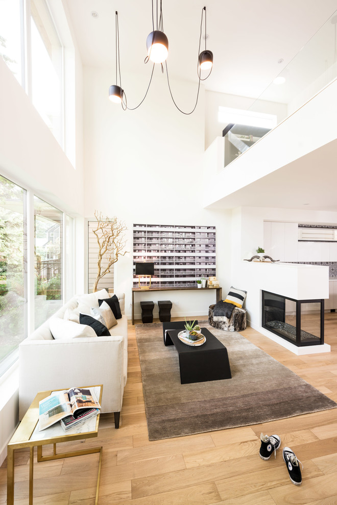Immagine di un soggiorno design aperto con pareti bianche, pavimento in legno massello medio e camino bifacciale