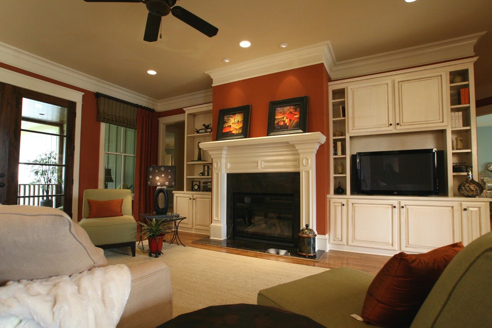 Idées déco pour un salon classique avec un mur orange, un sol en bois brun, une cheminée standard, un manteau de cheminée en bois et un téléviseur encastré.
