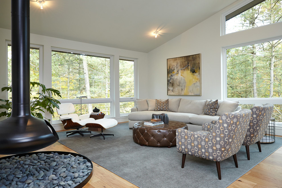 Esempio di un soggiorno moderno con pareti bianche, pavimento in legno massello medio e camino sospeso