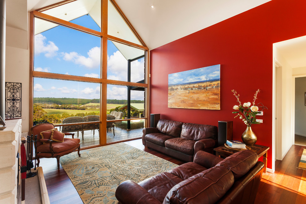 Exemple d'un salon chic ouvert avec une salle de réception, un mur rouge, un sol en bois brun, un sol marron et un plafond cathédrale.