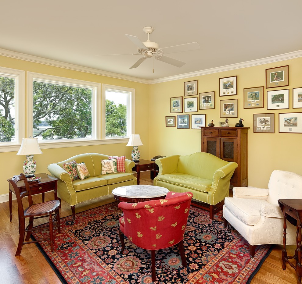 Design ideas for a classic enclosed living room in Charleston with yellow walls and light hardwood flooring.
