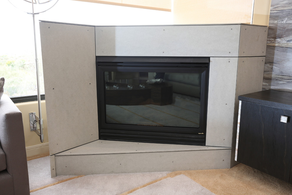 Cette image montre un grand salon design ouvert avec un mur gris, moquette, une cheminée d'angle, un manteau de cheminée en béton et un téléviseur fixé au mur.