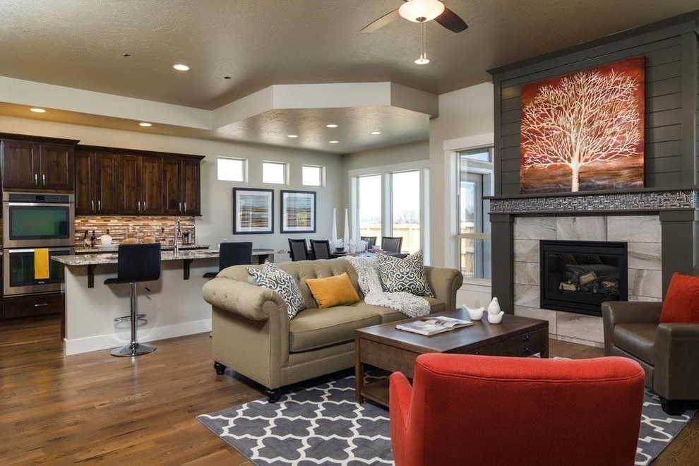 Offenes Klassisches Wohnzimmer mit beiger Wandfarbe, braunem Holzboden, Kamin, gefliester Kaminumrandung und TV-Wand in Boise