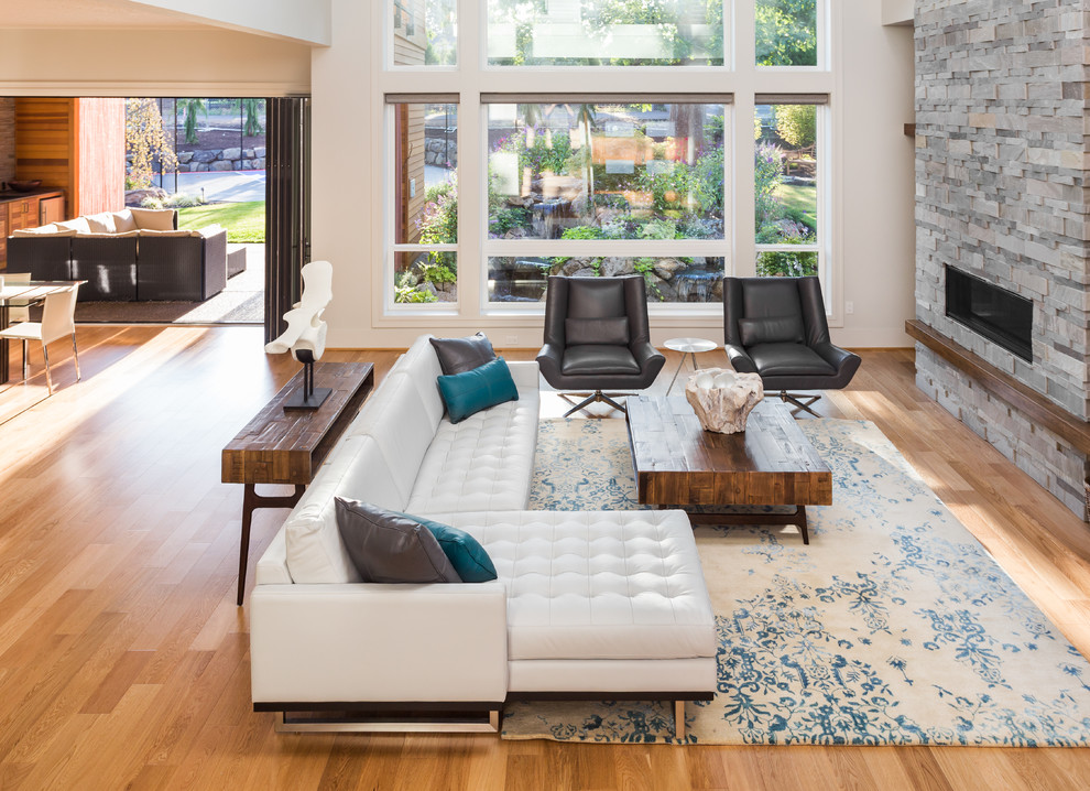 Idées déco pour un très grand salon mansardé ou avec mezzanine contemporain avec un mur blanc, parquet clair, une cheminée standard, un manteau de cheminée en pierre et un téléviseur fixé au mur.