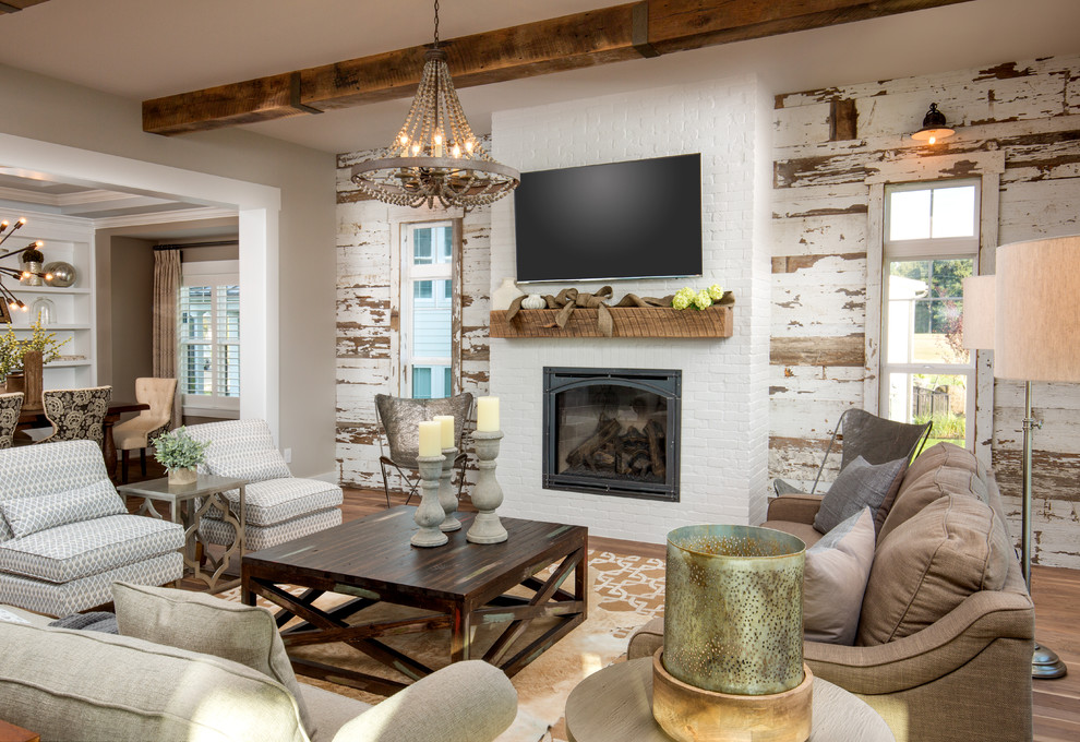 Cette image montre un salon rustique avec un mur gris, un sol en bois brun, une cheminée standard, un manteau de cheminée en brique, un téléviseur fixé au mur et un sol marron.