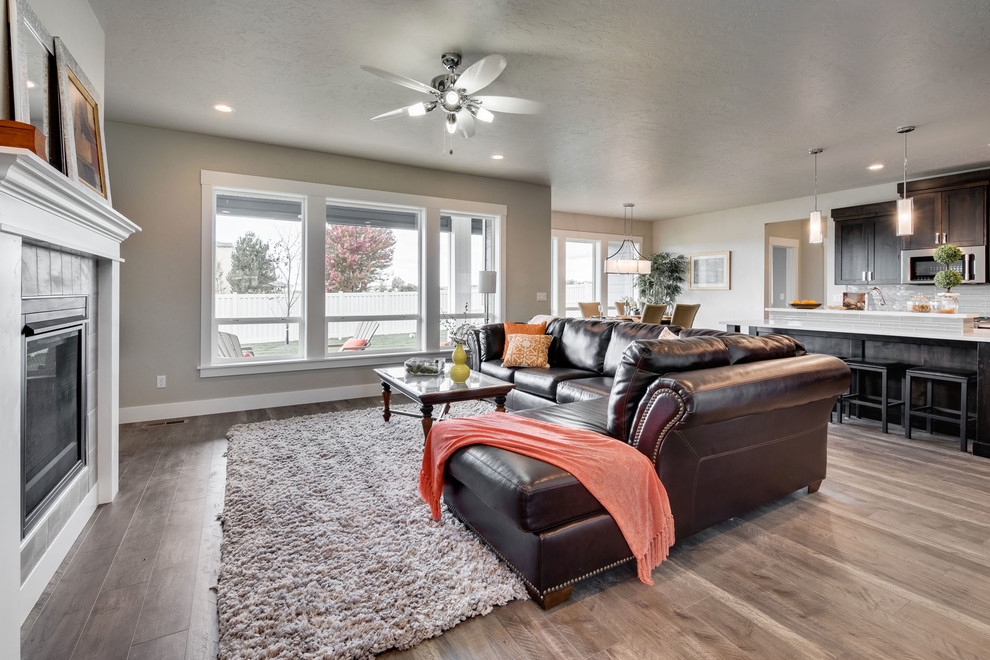 Mittelgroßes, Offenes Klassisches Wohnzimmer mit beiger Wandfarbe, braunem Holzboden, Kamin, gefliester Kaminumrandung, TV-Wand und braunem Boden in Boise