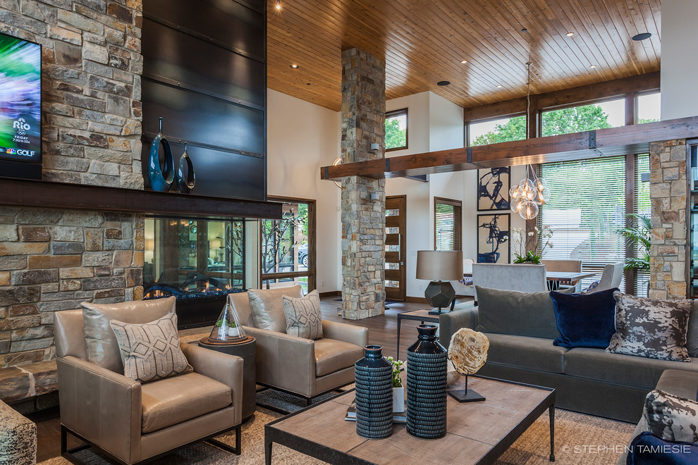 Design ideas for an expansive contemporary open plan living room in Portland with dark hardwood flooring, a two-sided fireplace, a stone fireplace surround and a wall mounted tv.