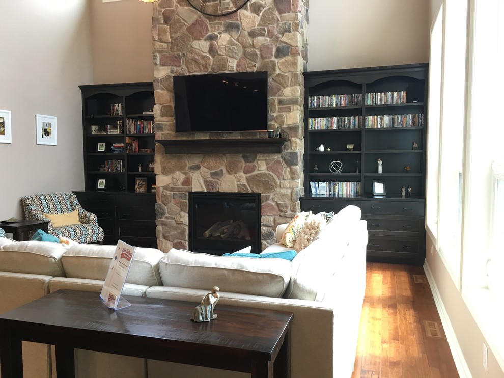 This is an example of a medium sized classic formal enclosed living room in Other with beige walls, medium hardwood flooring, a standard fireplace, a stone fireplace surround, a wall mounted tv and beige floors.