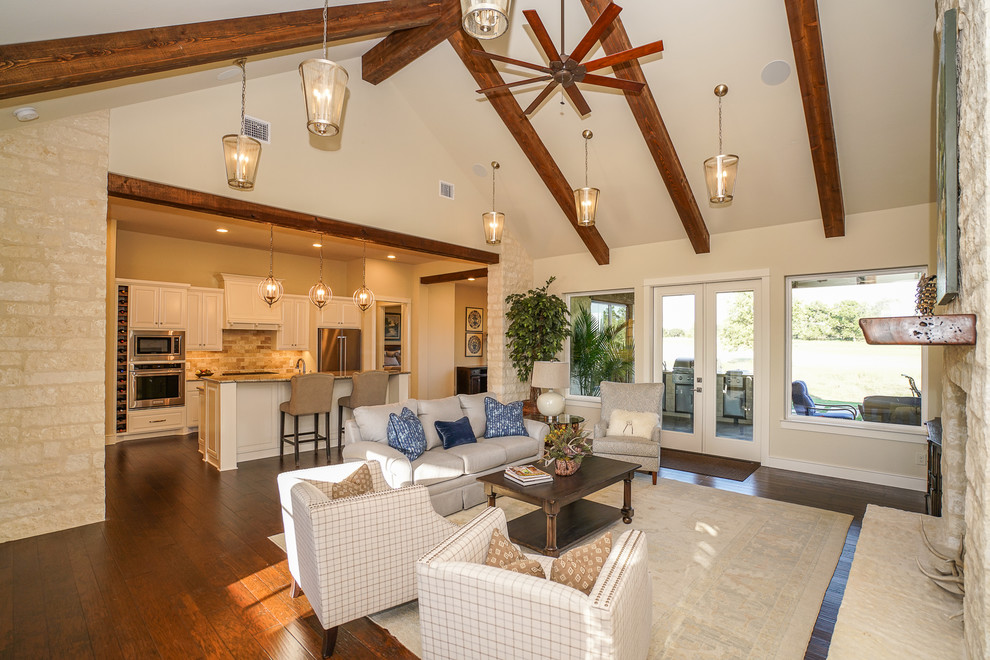 Inspiration for a medium sized country formal open plan living room in Austin with beige walls, medium hardwood flooring, a standard fireplace, a stone fireplace surround, a wall mounted tv and brown floors.