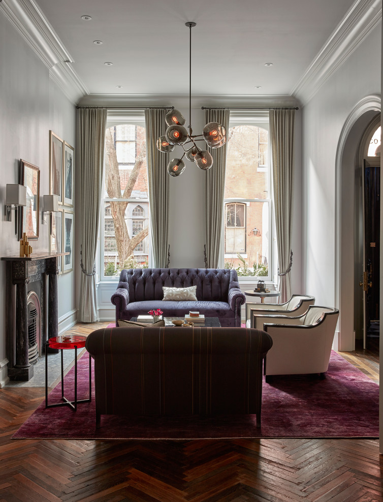 Пример оригинального дизайна: гостиная комната в викторианском стиле с белыми стенами, паркетным полом среднего тона, стандартным камином и фиолетовым полом