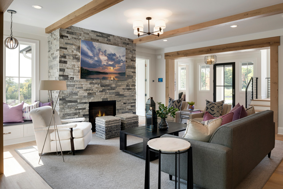 Cette photo montre un salon chic ouvert et de taille moyenne avec un mur blanc, un sol en bois brun, une cheminée standard, un manteau de cheminée en pierre et un sol marron.