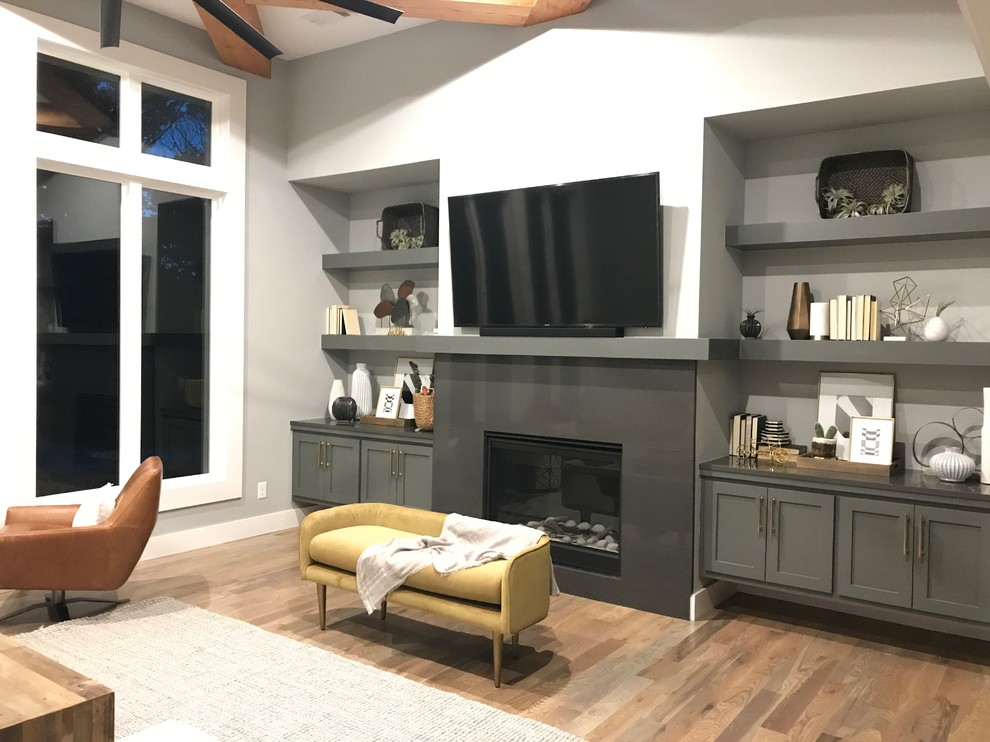Свежая идея для дизайна: открытая гостиная комната среднего размера в стиле неоклассика (современная классика) с серыми стенами, светлым паркетным полом, стандартным камином, телевизором на стене и серым полом - отличное фото интерьера