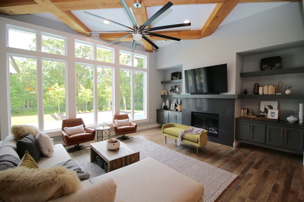 На фото: открытая гостиная комната среднего размера в стиле неоклассика (современная классика) с серыми стенами, светлым паркетным полом, стандартным камином, телевизором на стене и серым полом