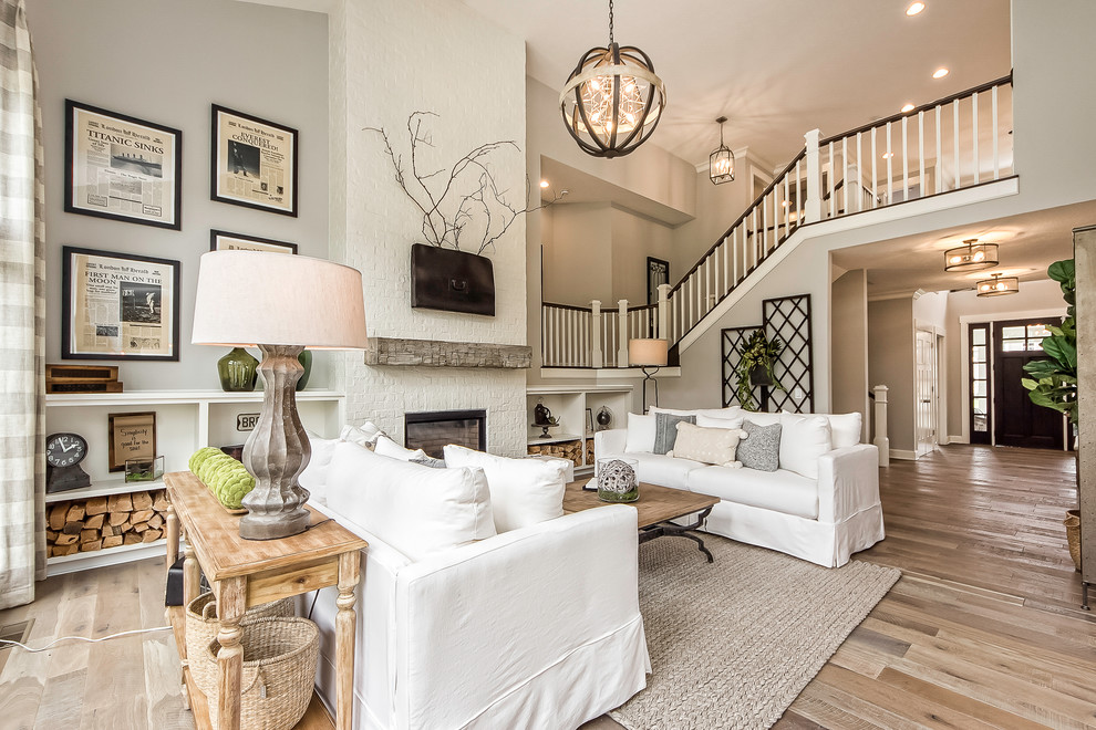 Elegant loft-style living room photo in Columbus with a standard fireplace, a brick fireplace and a wall-mounted tv