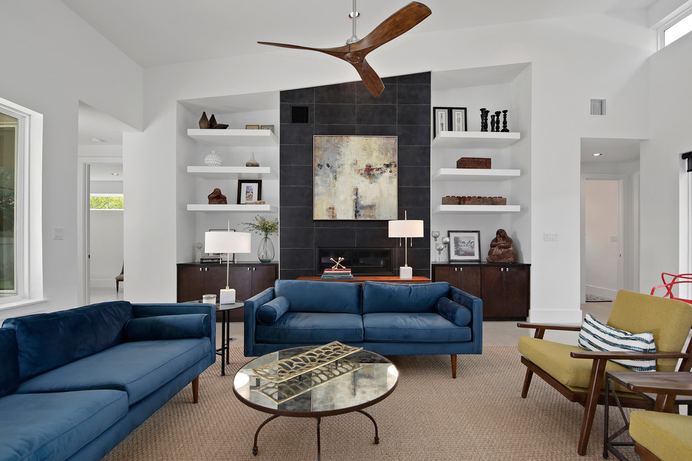 Пример оригинального дизайна: гостиная комната в стиле неоклассика (современная классика) с белыми стенами, стандартным камином и синим диваном