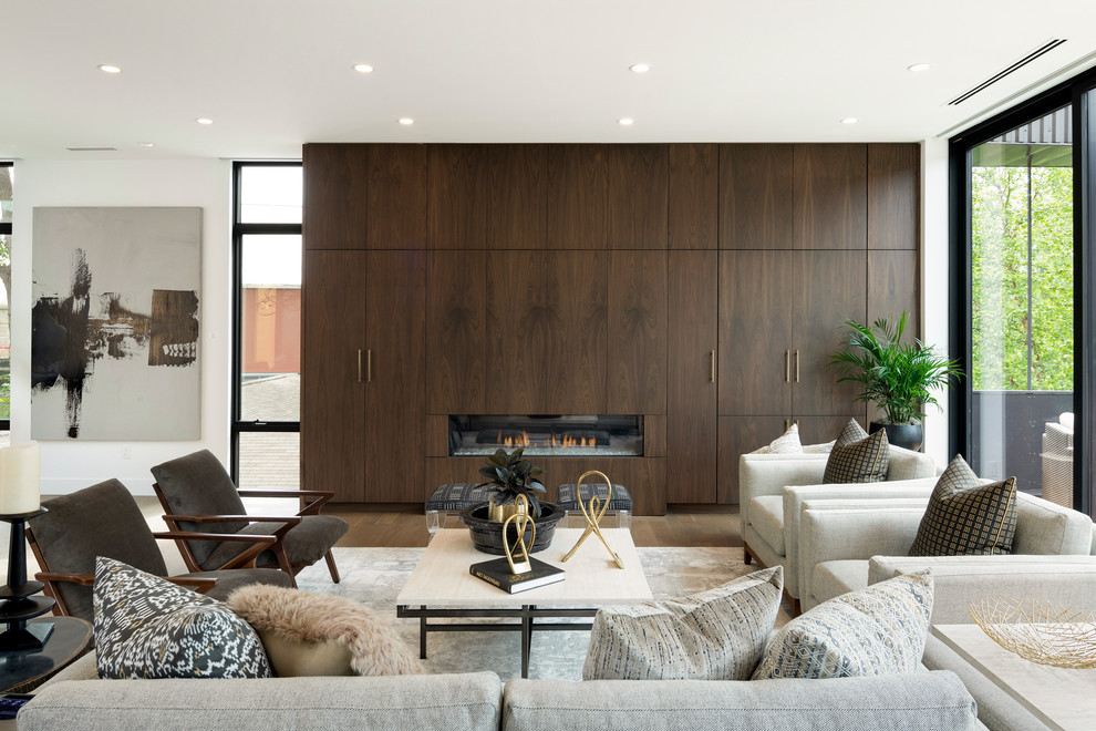 Inspiration for a large modern open plan living room in Minneapolis with white walls, light hardwood flooring, a ribbon fireplace, a wooden fireplace surround, a concealed tv and grey floors.