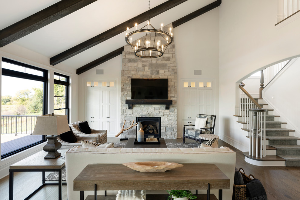 Inspiration for a farmhouse living room in Minneapolis with white walls, medium hardwood flooring, a standard fireplace, a stone fireplace surround, a wall mounted tv and brown floors.