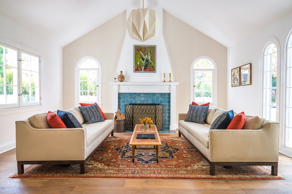 Klassisches Wohnzimmer mit beiger Wandfarbe, braunem Holzboden, Kamin, gefliester Kaminumrandung und braunem Boden in Los Angeles