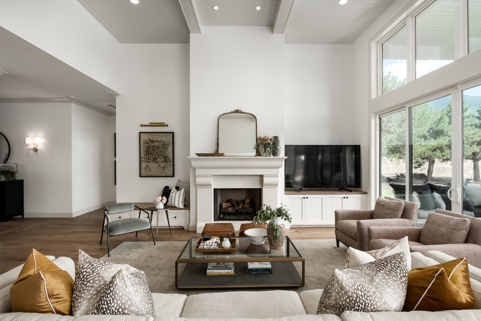 На фото: открытая гостиная комната в стиле кантри с белыми стенами, паркетным полом среднего тона, стандартным камином, отдельно стоящим телевизором и коричневым полом