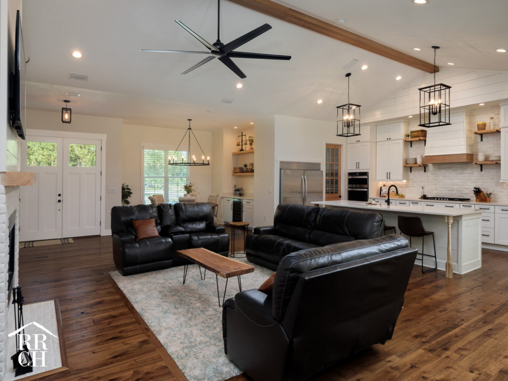 Country open plan living room in Miami with white walls, a standard fireplace, a brick fireplace surround, a wall mounted tv and brown floors.