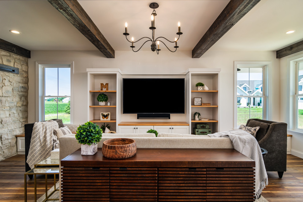 Idee per un soggiorno country aperto con pareti bianche, pavimento in legno massello medio, TV a parete, pavimento marrone e travi a vista