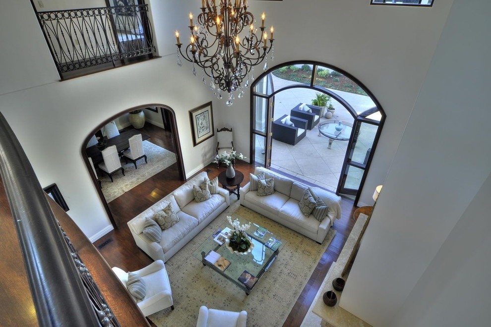 This is an example of a large mediterranean formal mezzanine living room in Santa Barbara with white walls, dark hardwood flooring, a standard fireplace, a brick fireplace surround and no tv.