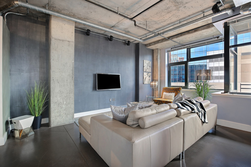 Diseño de salón abierto urbano pequeño sin chimenea con paredes azules, suelo de cemento y televisor colgado en la pared